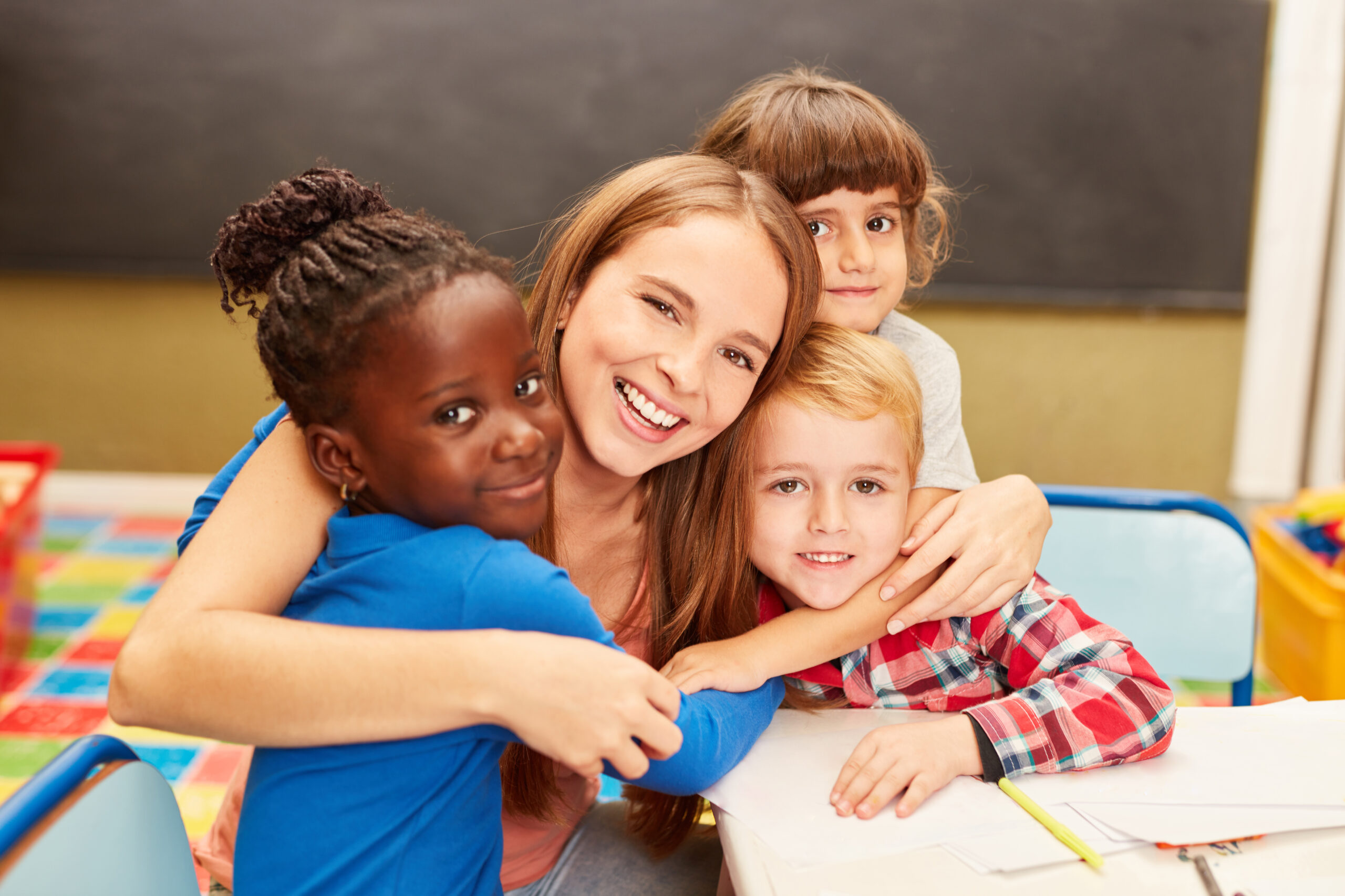 Young,Woman,As,A,Childminder,Or,Teacher,Hugs,Children,In Children at Soans Christian Academy Christian daycare