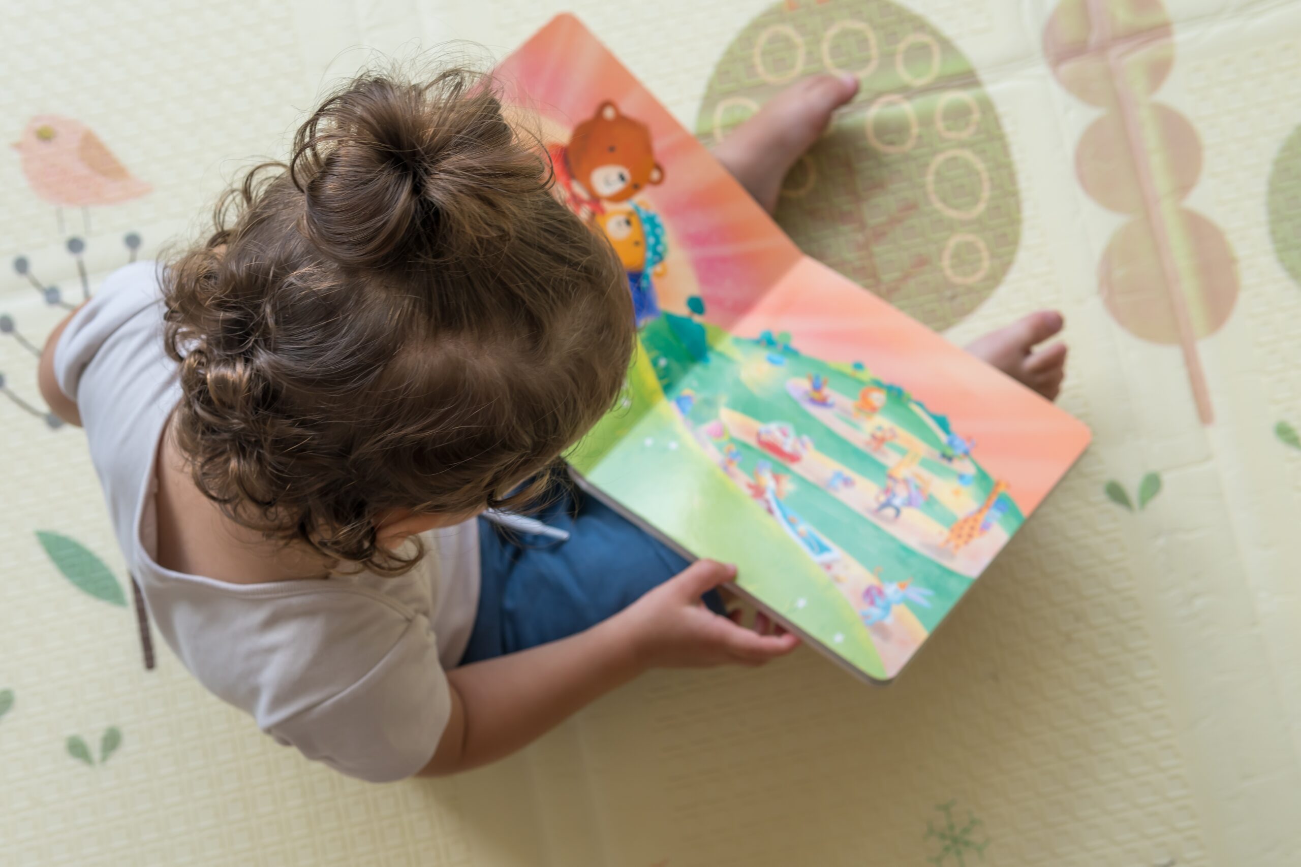 Infant,Sitting,On,A,Playmat,And,Reading,A,Coloful,Children’s Infant care at Soans Christian Academy